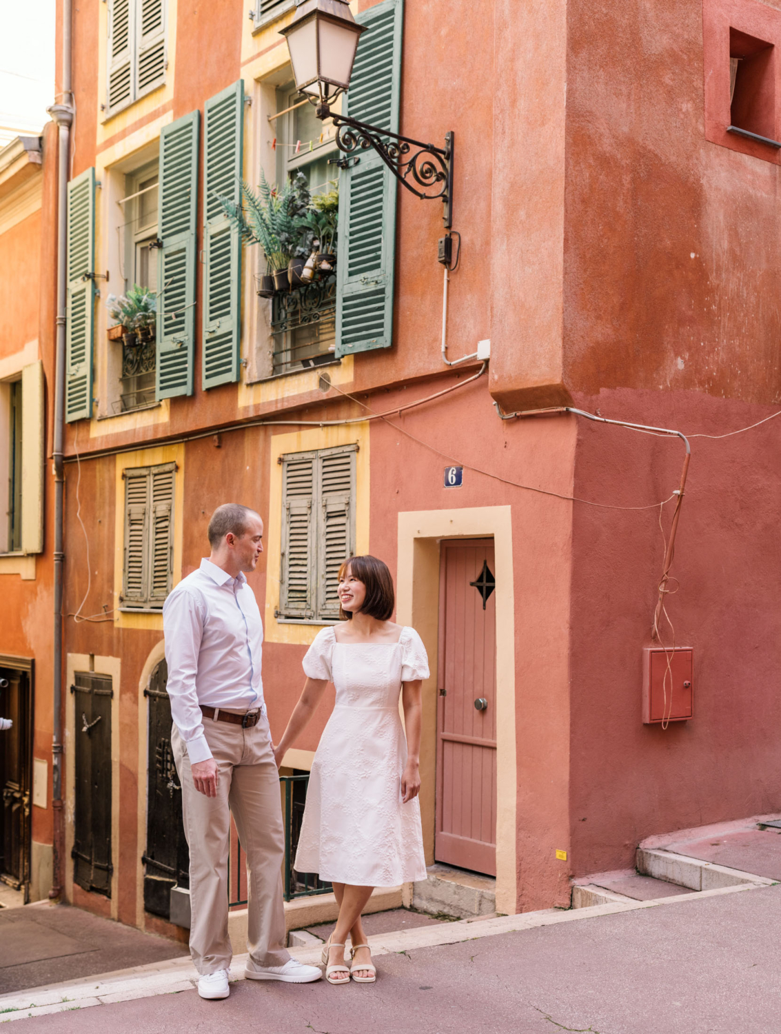 happy couple pose in front of colorful building in nice france