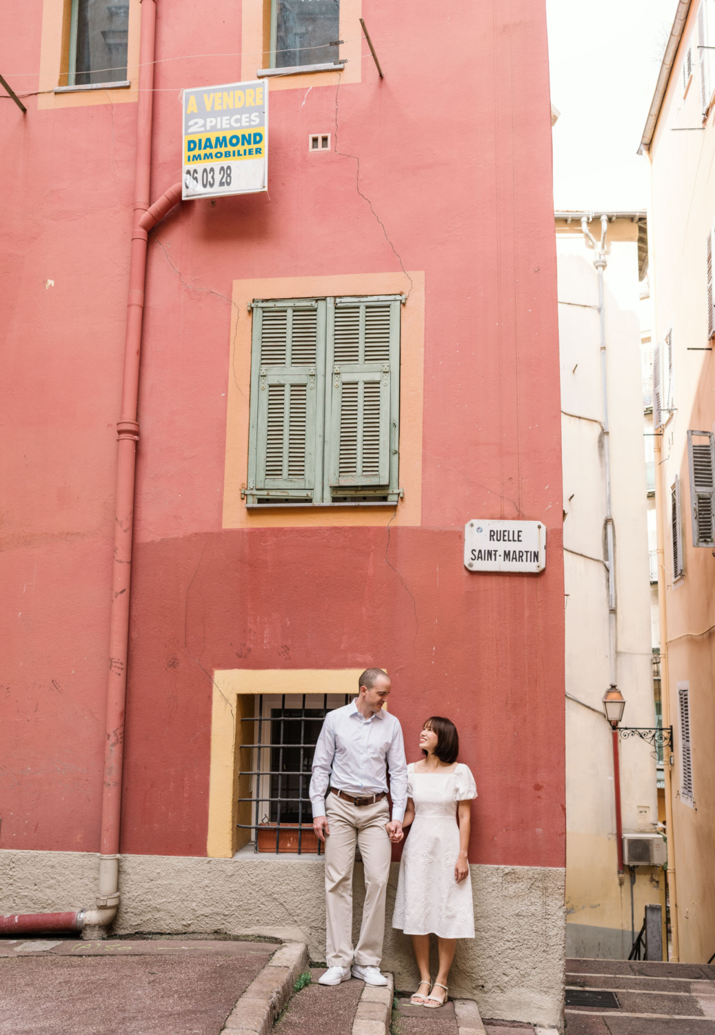 cute couple pose in front of orange building in nice france