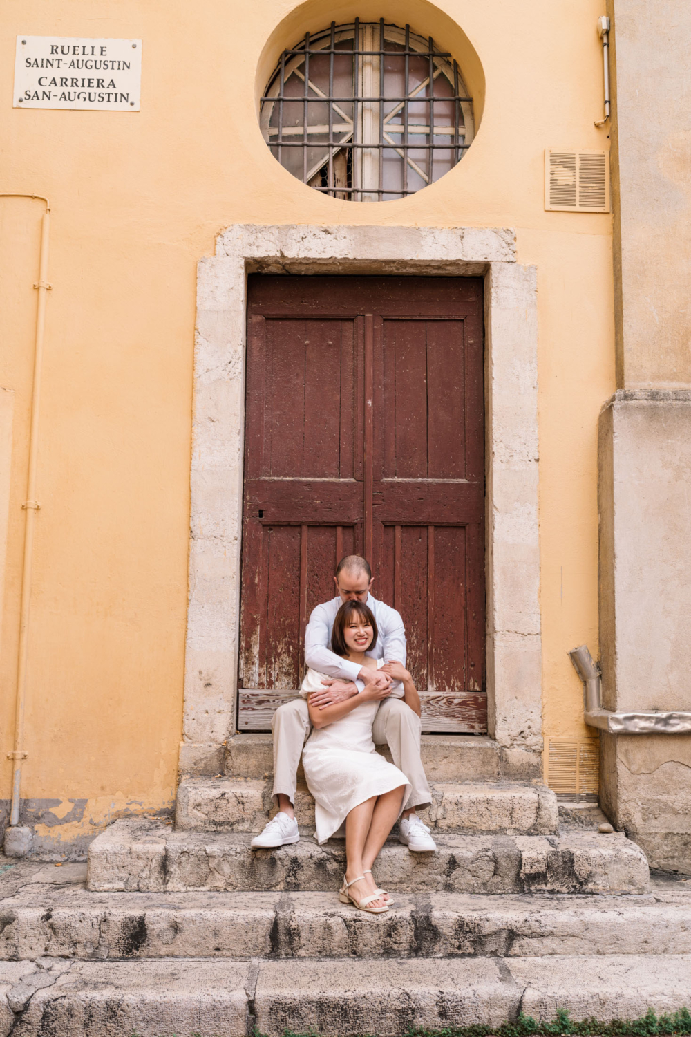 man kisses woman's head as they relax on a staircase in nice france