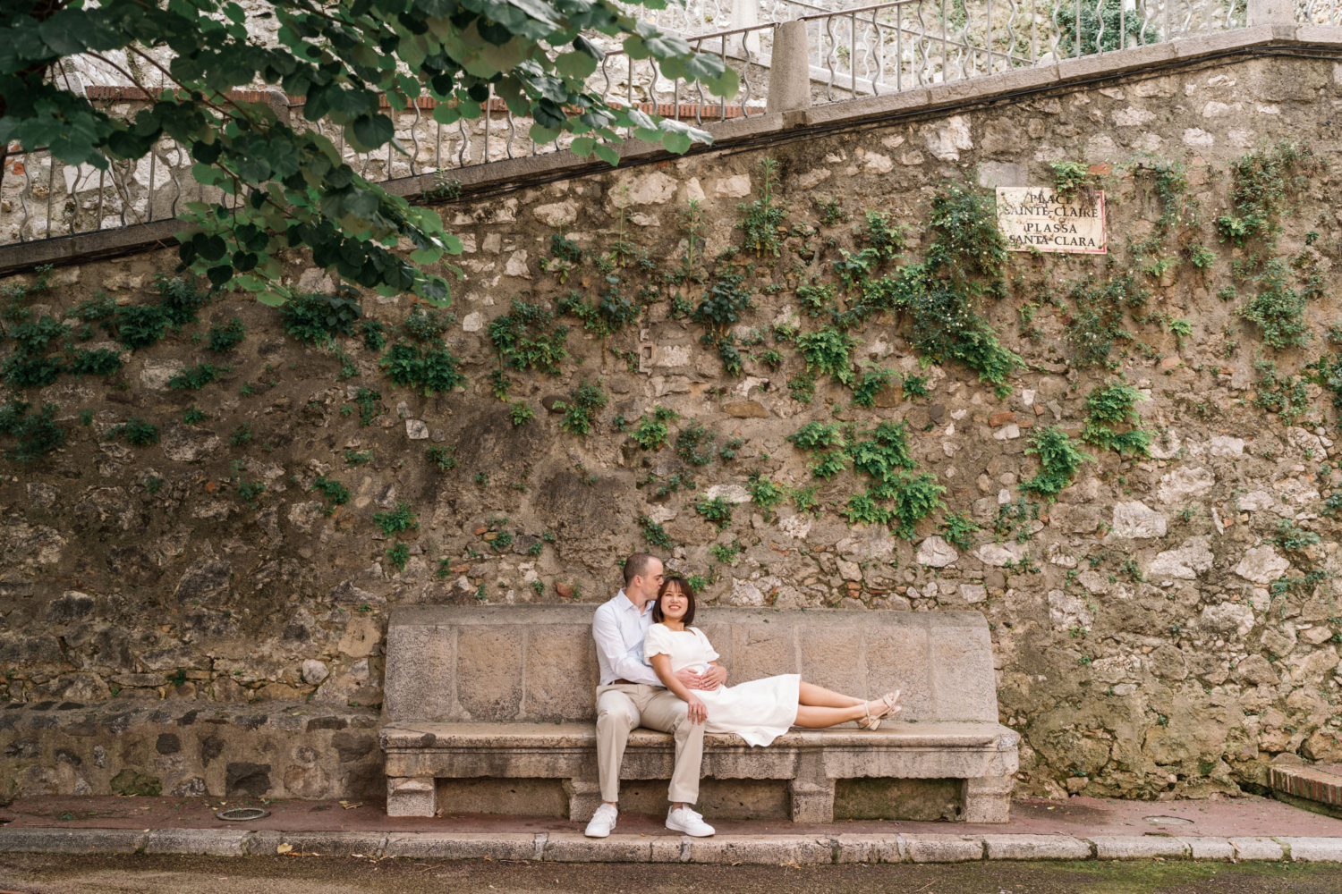 man kisses woman's head as they relax on concrete bench