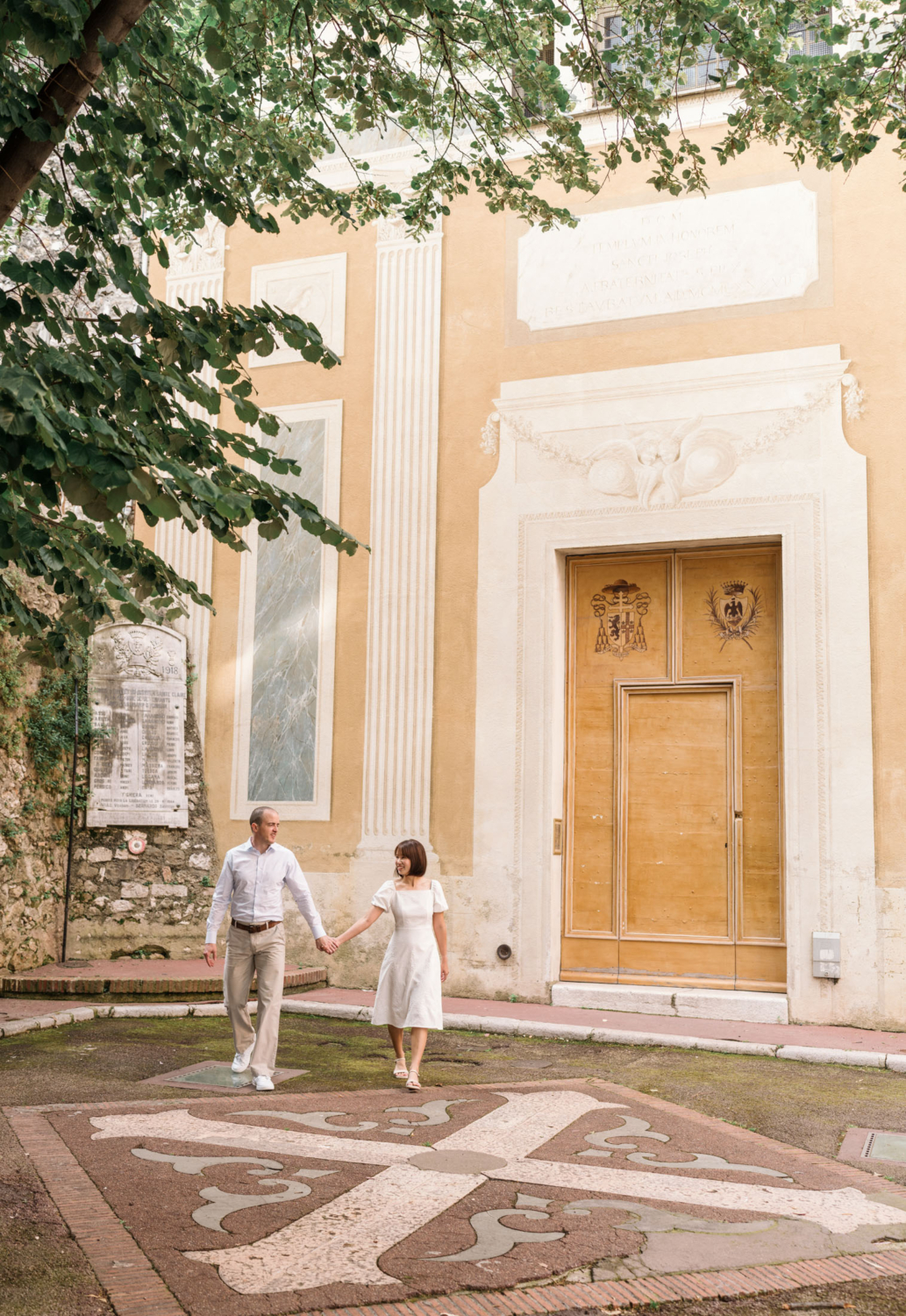 man and woman walk holding hands in front of yellow church in nice france