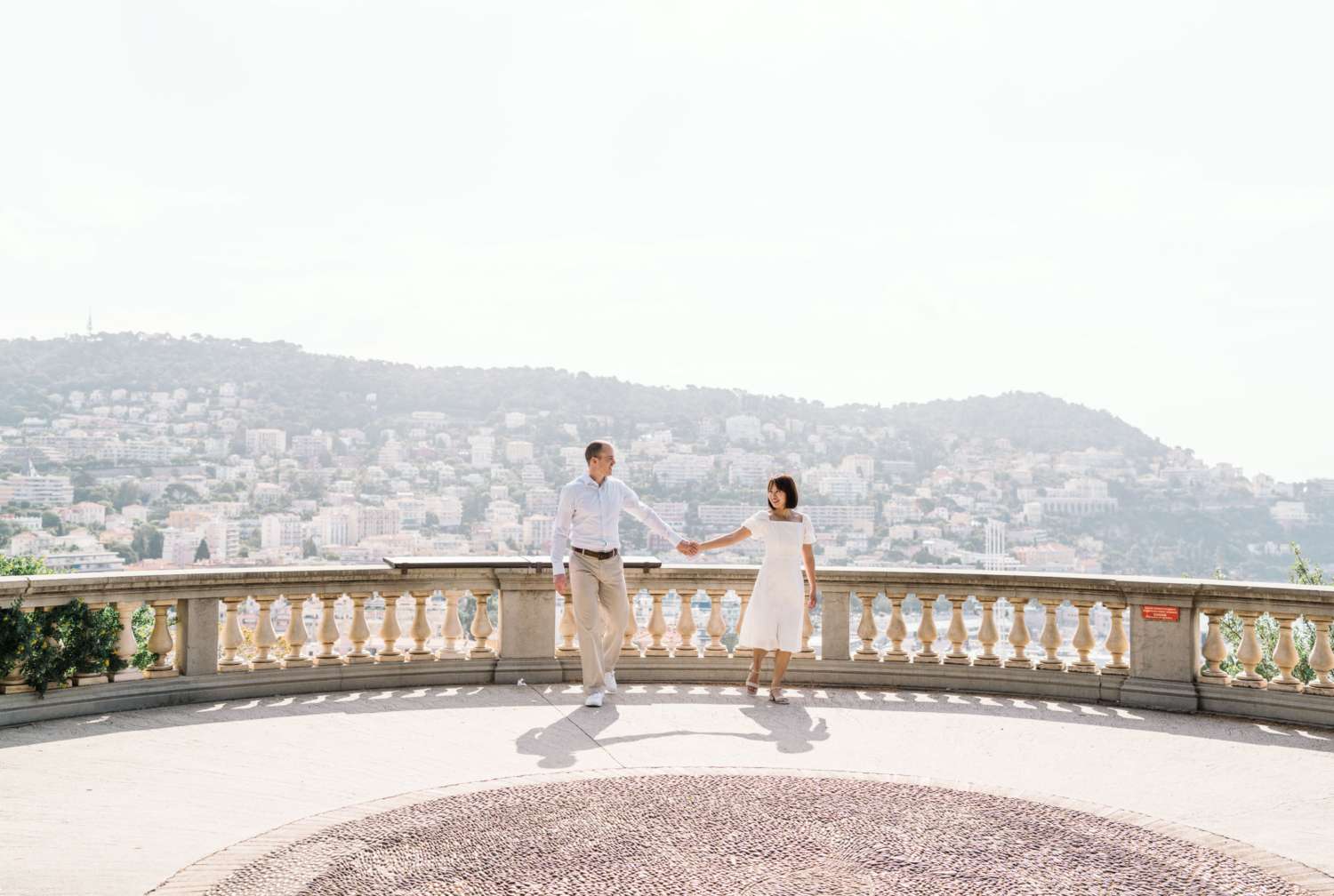 man and woman walk holding hands with gorgeous view in nice france