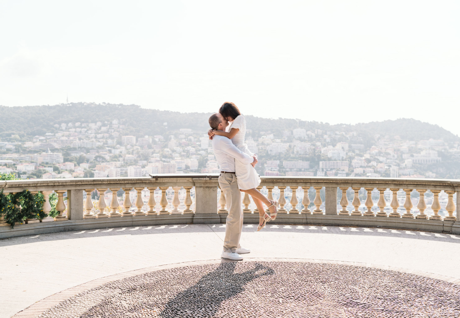 man lifts woman in air with beautiful view in nice france