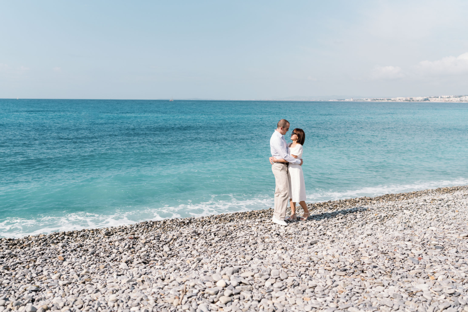 couple embrace with view of blue sea behind them in nice france