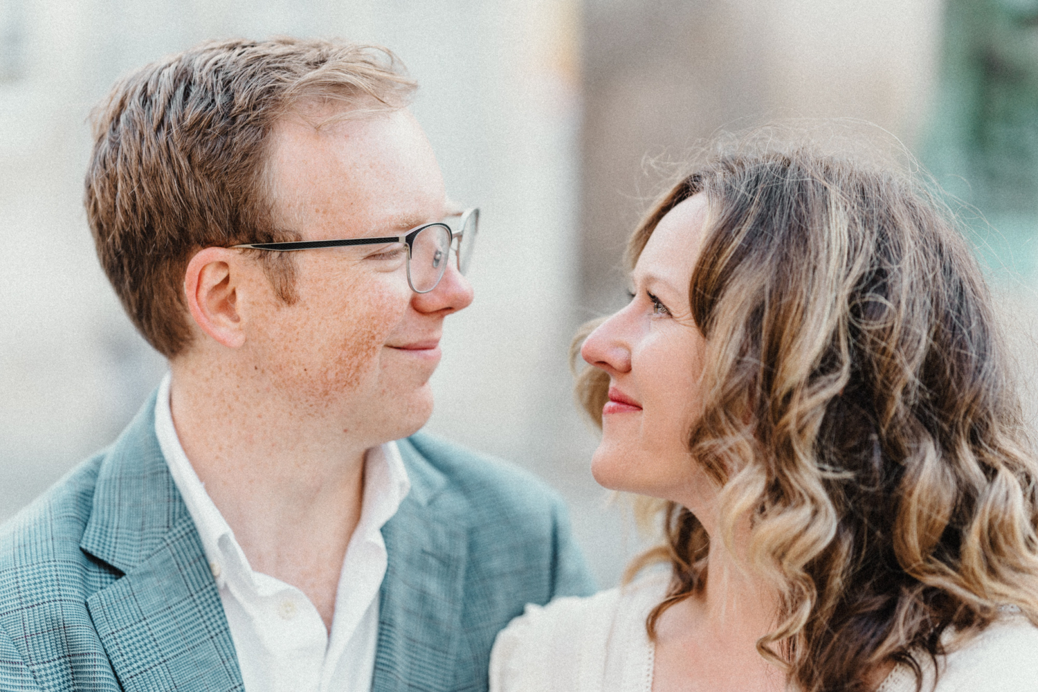 engaged couple smile at each other