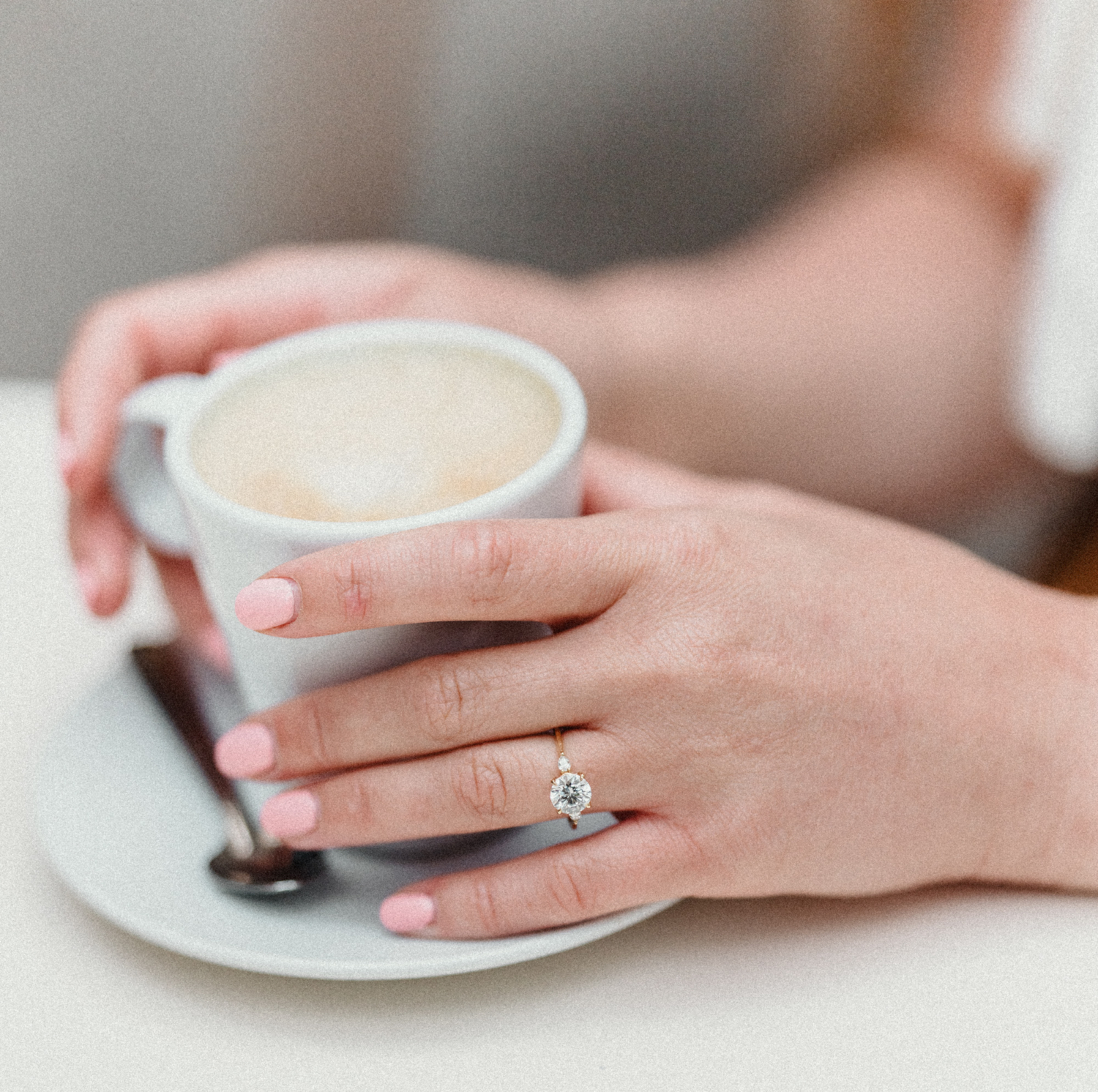 woman holds coffee wearing engagement ring