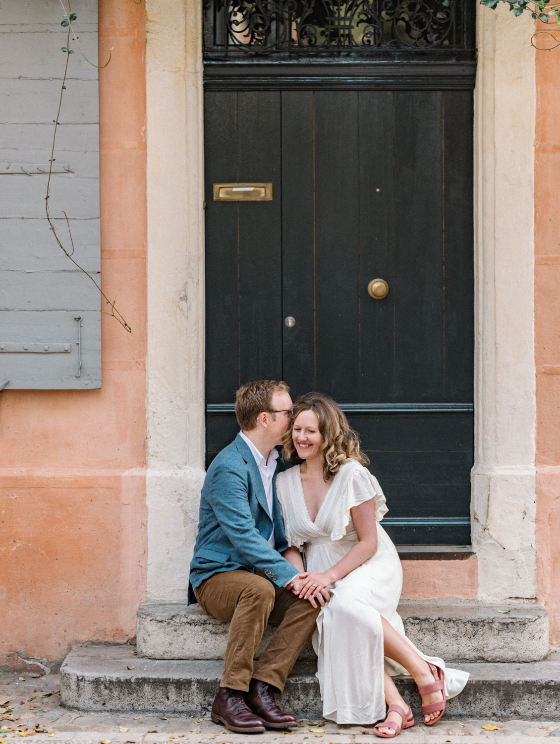 man whispers in womans ear sitting on staircase