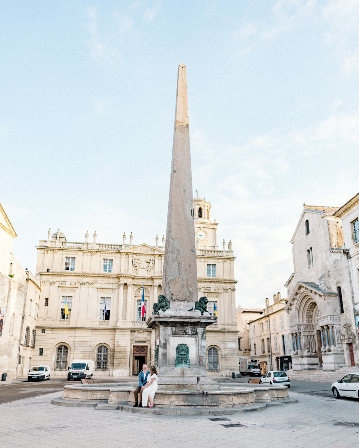 couple sit next to obelisk statue in arles france