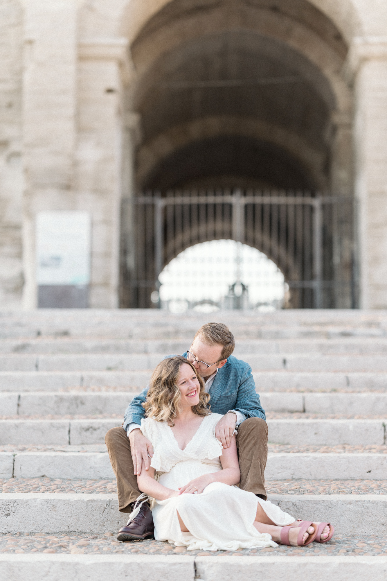 man kisses woman's head on steps during Engagement Photos In Provence