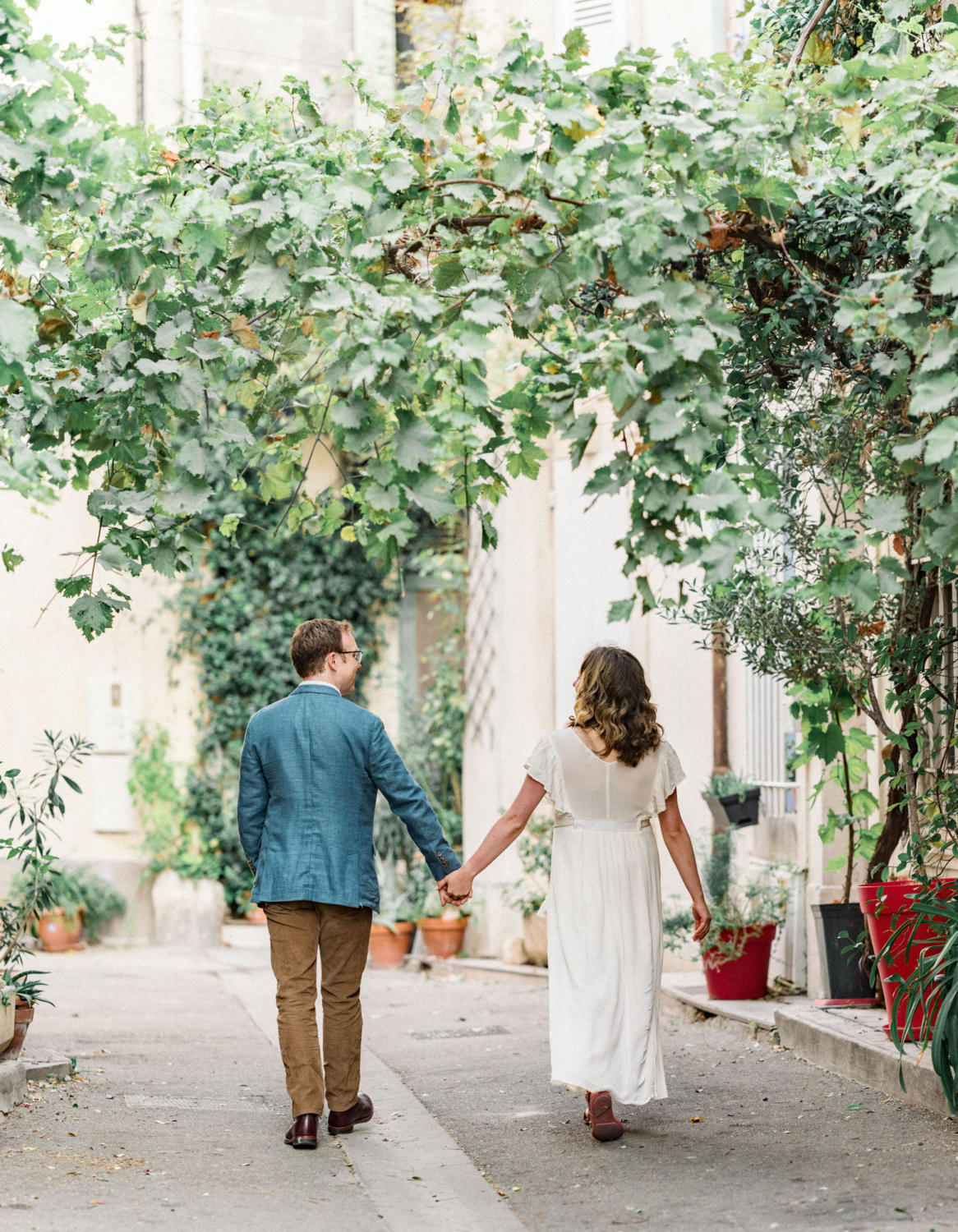 couple walk hand in hand under vines in arles france