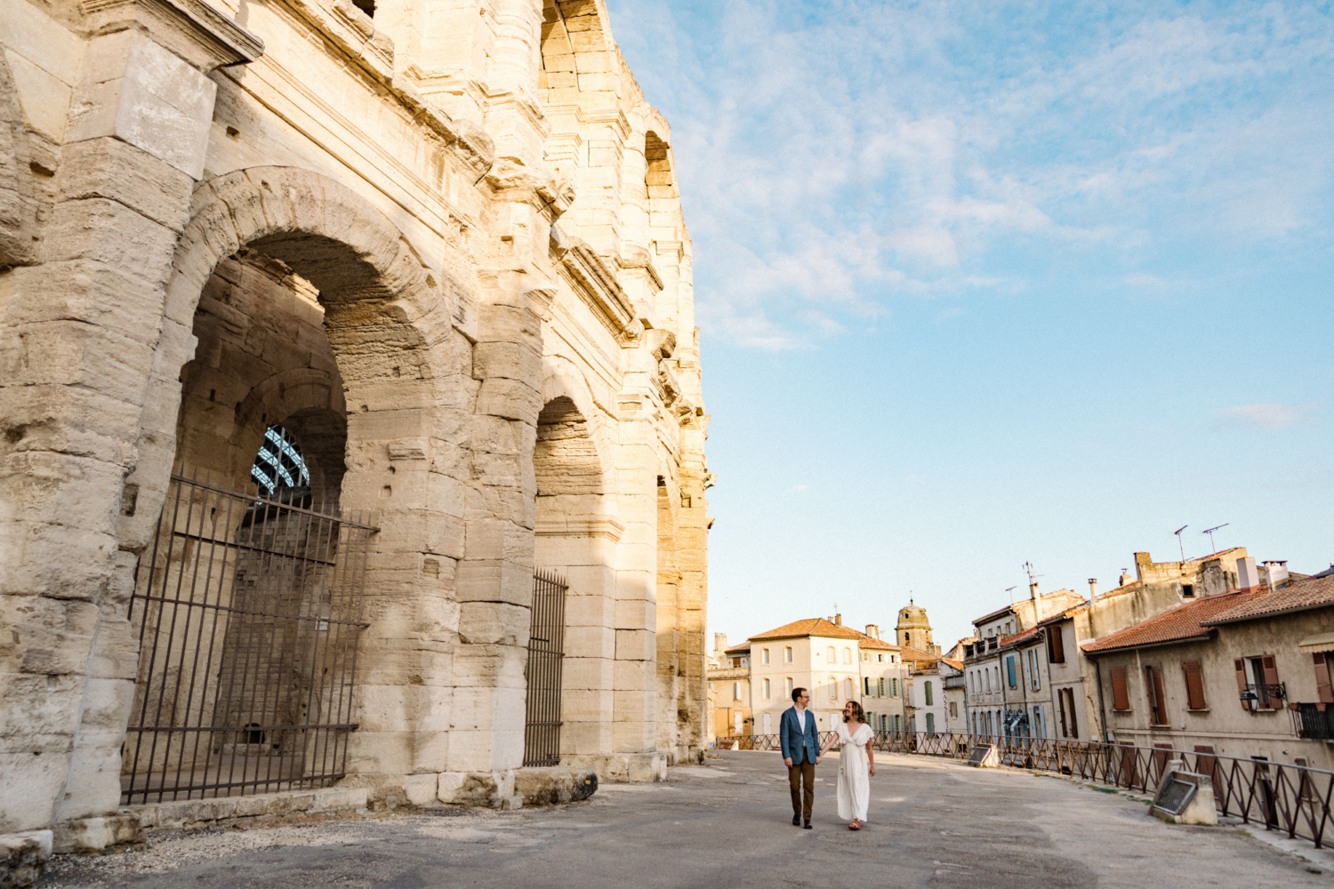 happy couple walk next to roman amphitheatre in arles france