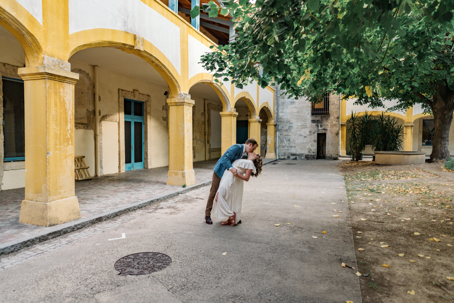 man dips and kisses woman near yellow archway