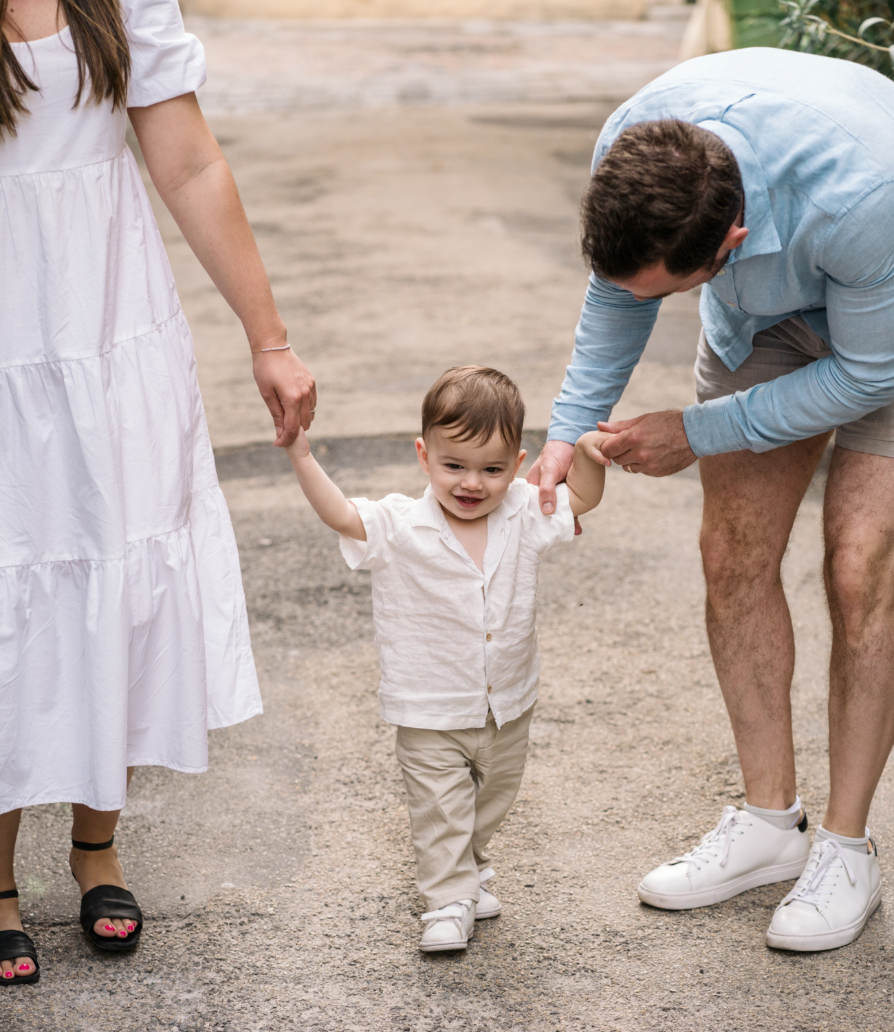 little boy laughs and walks with parents in arles france