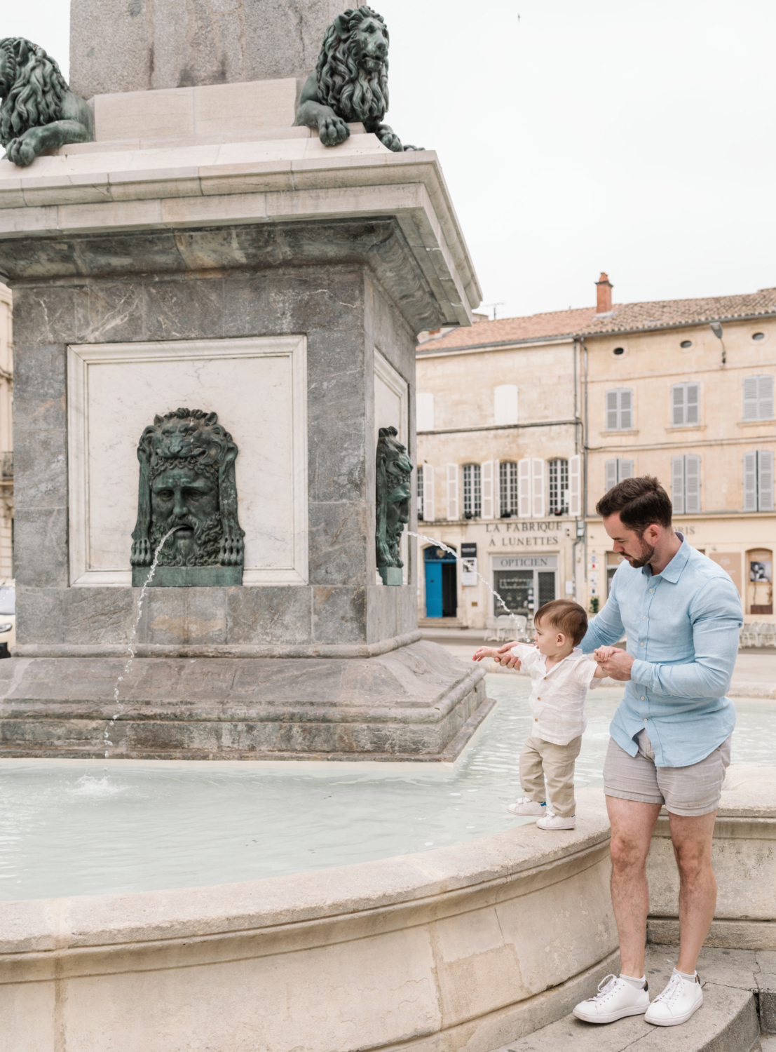 baby and dad play in fountain in arles france