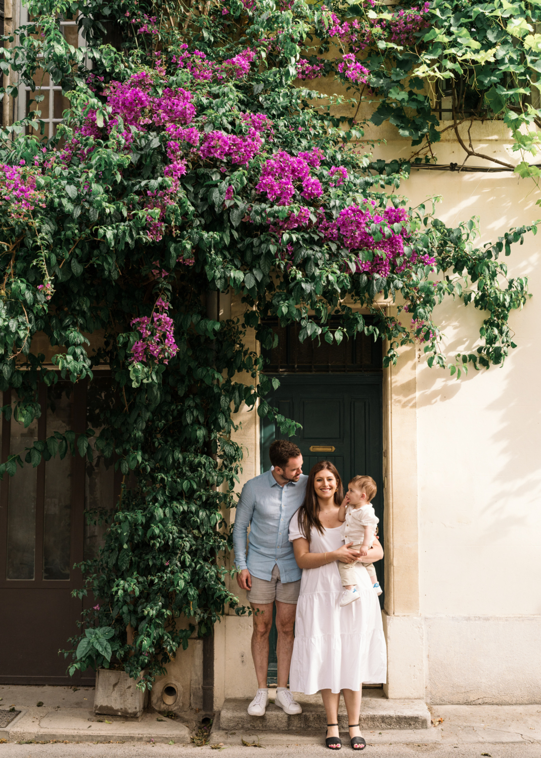 young couple hold baby under bougainvillea flowers in arles france