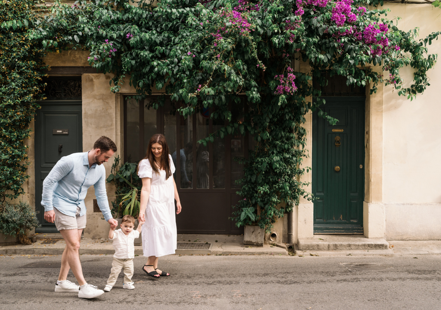 young family walk with baby under purple flowers in arles france