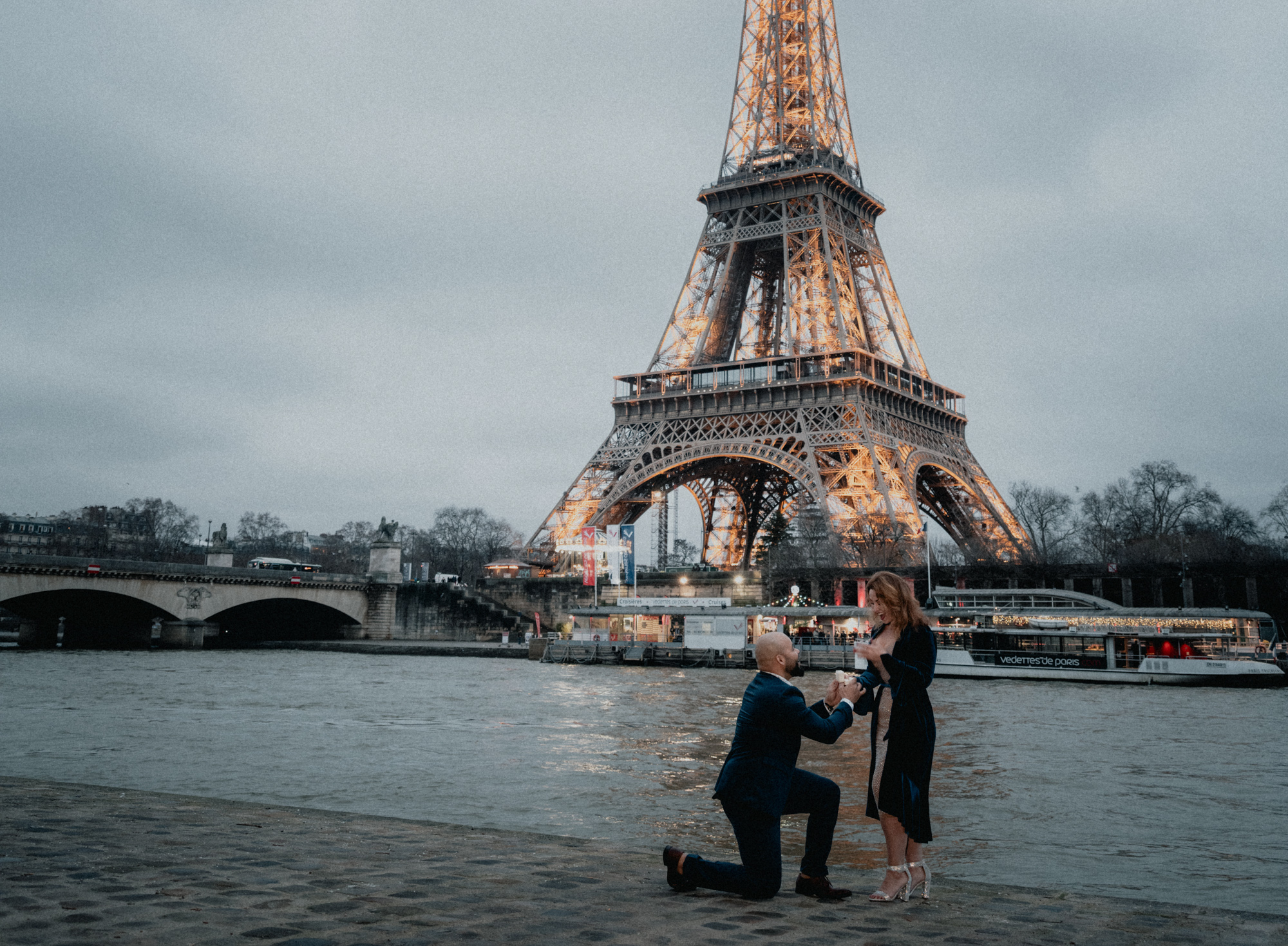 man gets on one knee to propose marriage at dusk at eiffel tower