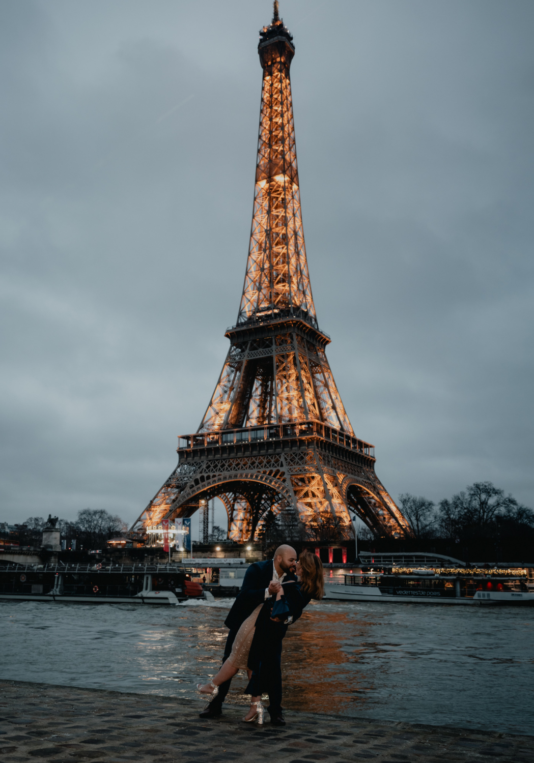 man dips woman after engagement with view of the eiffel tower