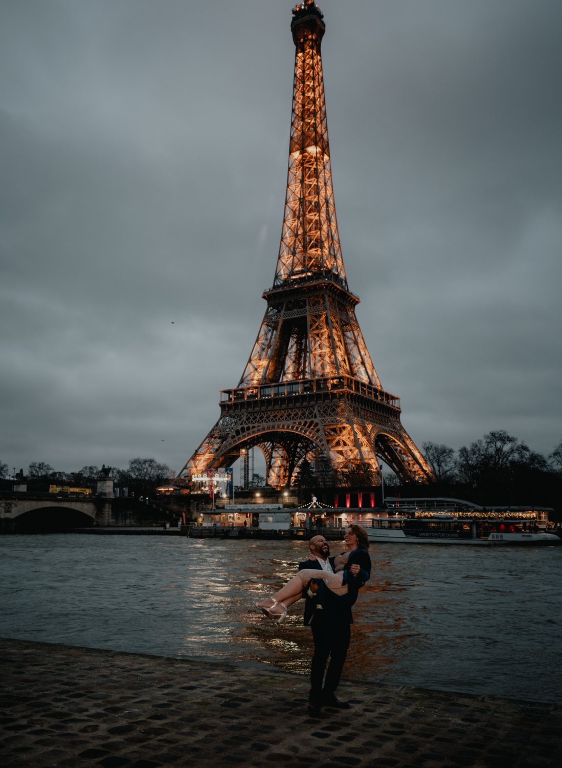 man lifts woman after their engagement in paris