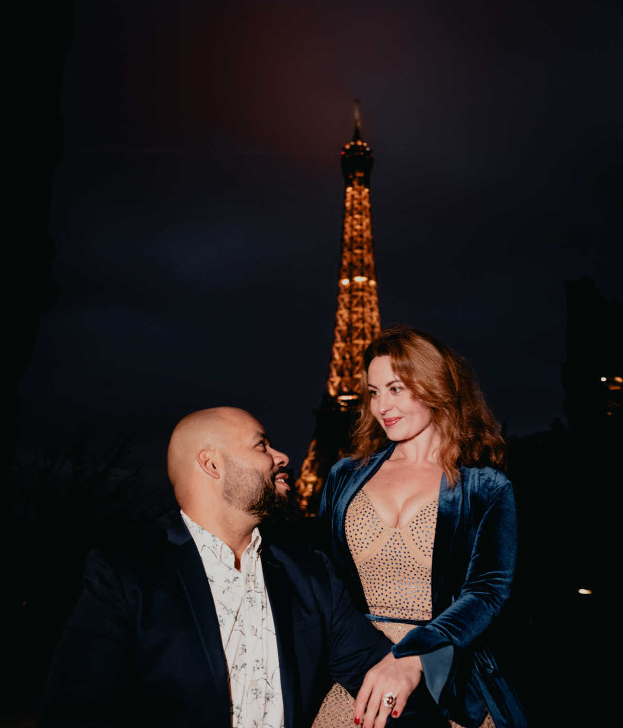 newly engaged couple pose at night at eiffel tower