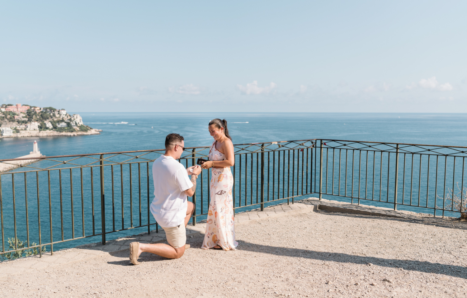 woman smiles broadly as man proposes with view of sea in nice france