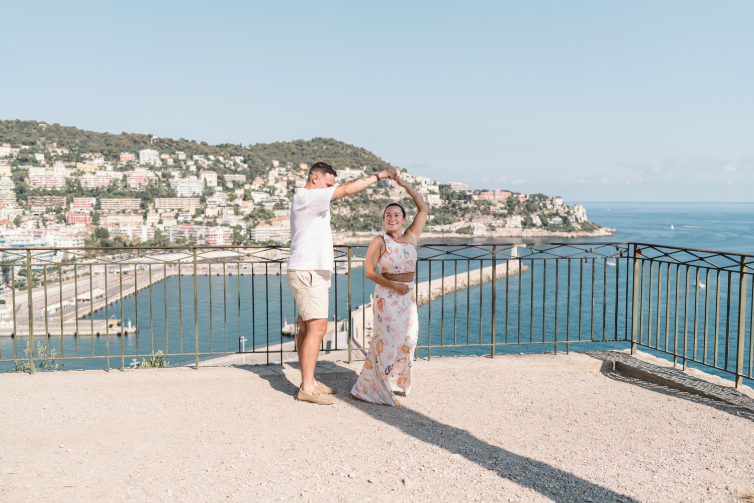 man twirls woman in a circle with view of sea in nice france