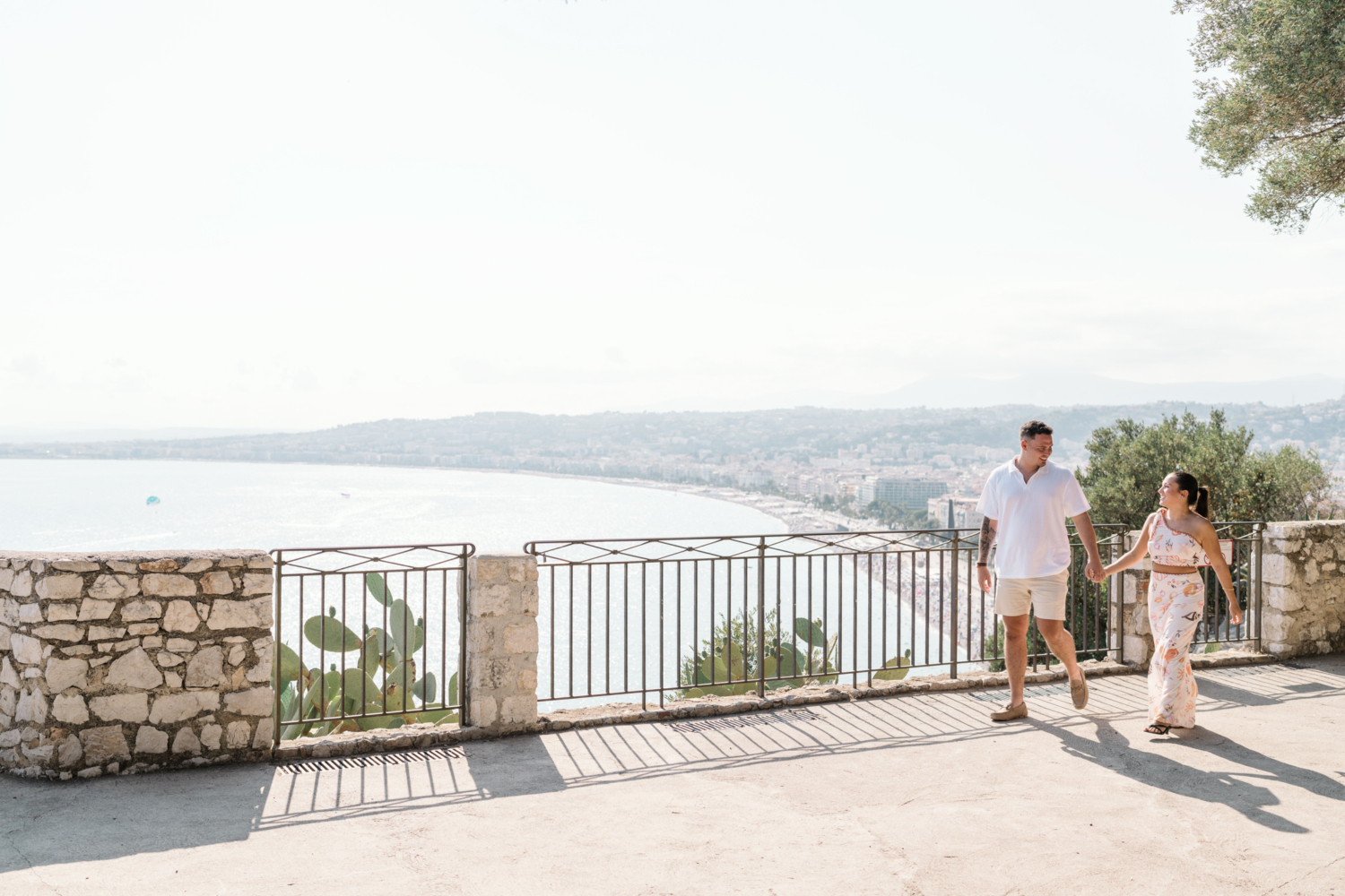 newly engaged couple hold hands and walk along the sea in nice france