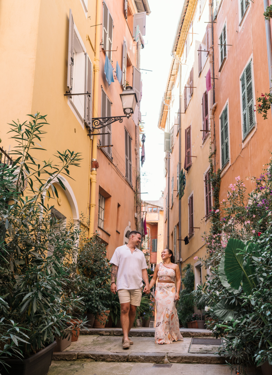 engaged couple walk hand in hand through plants in old town nice