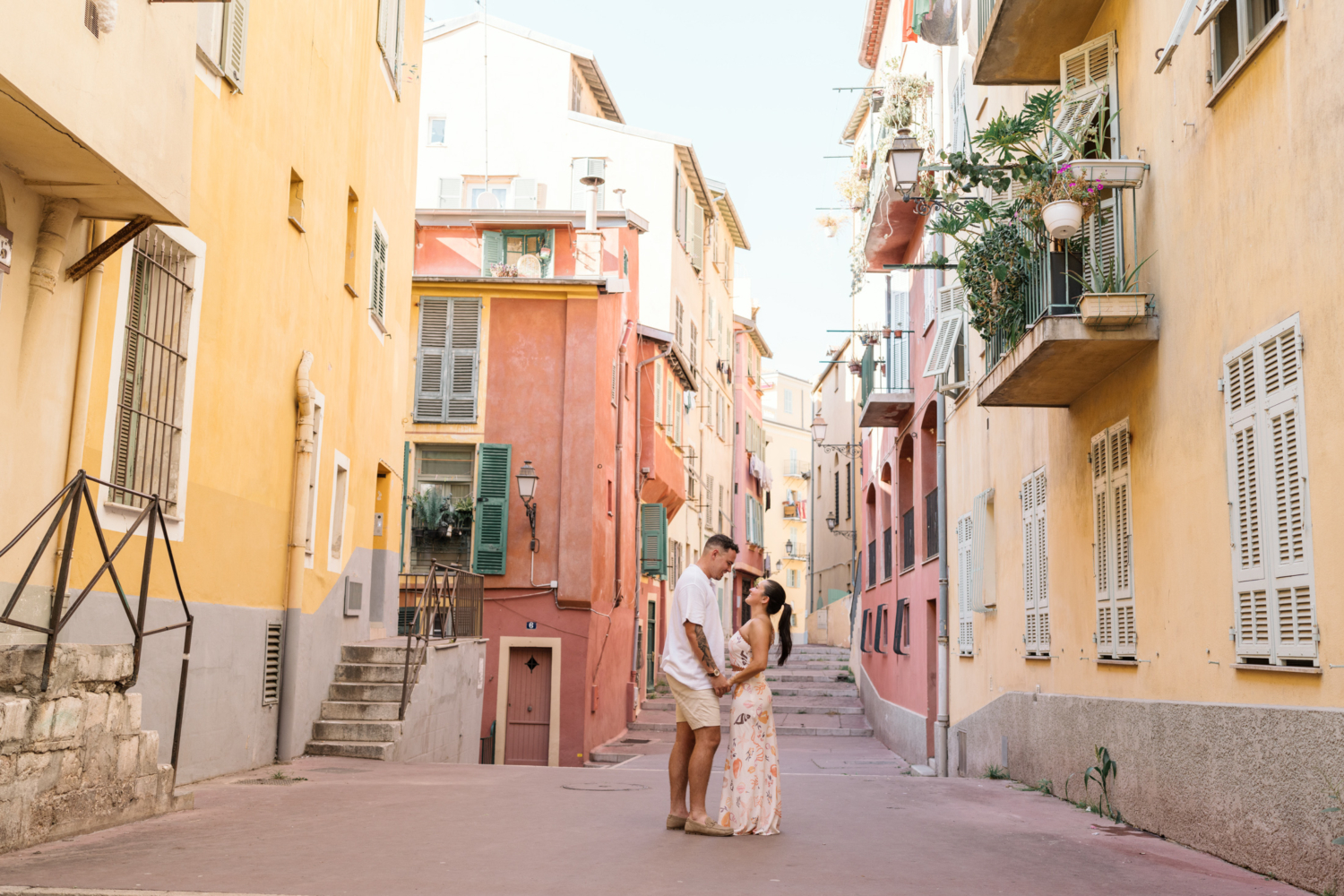 couple in love pose among colorful buildings in old nice france