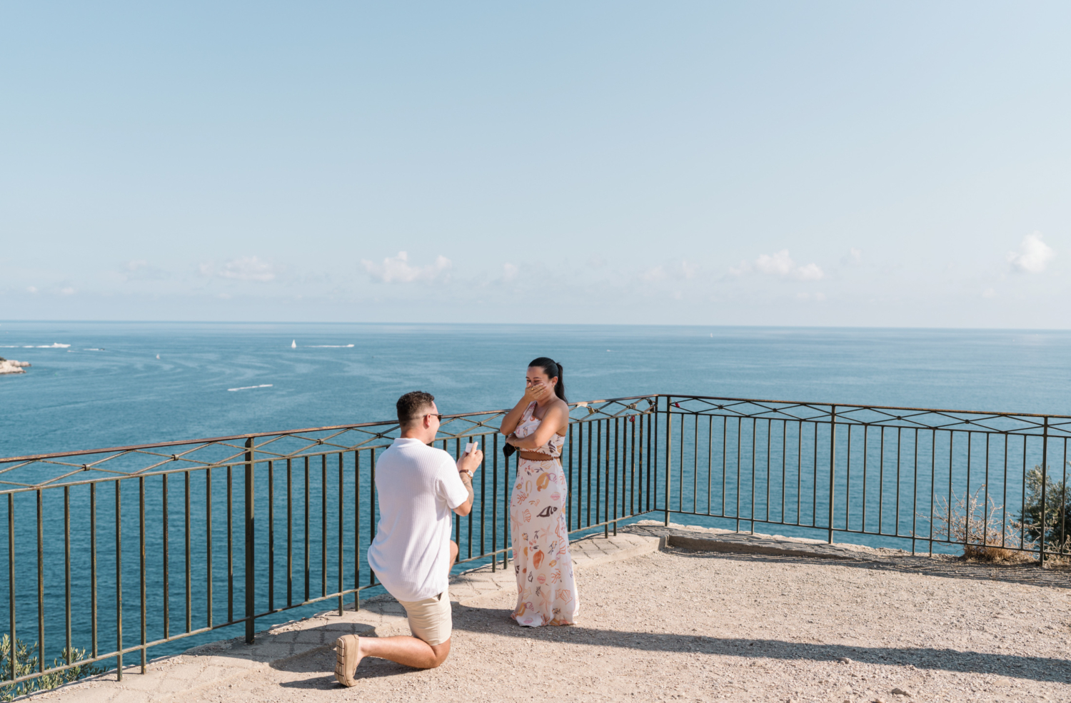 woman is shocked as man proposes with view of sea in nice france