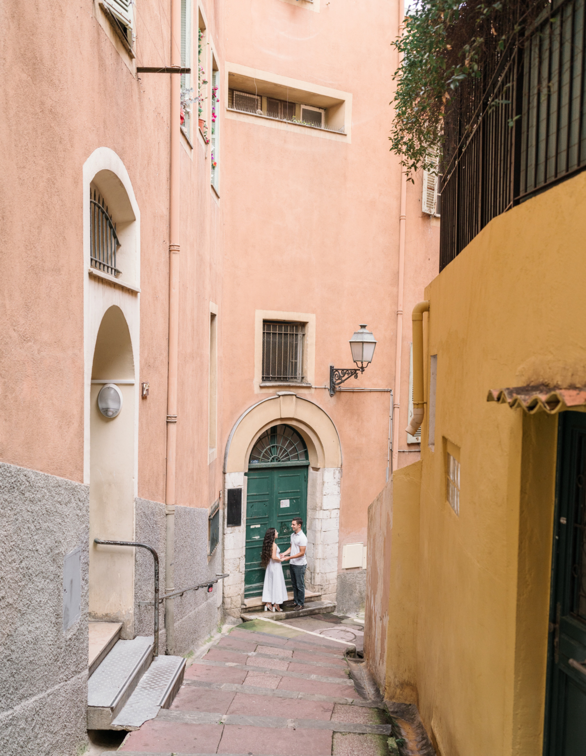 engaged couple pose in front of colorful green door in old town nice