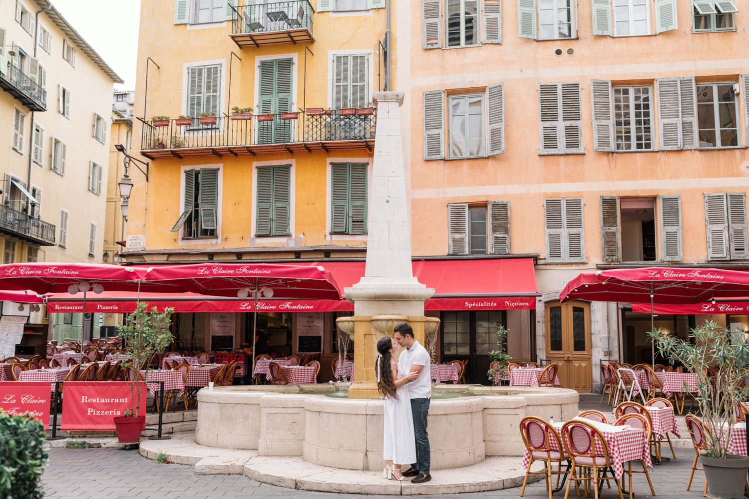 newly engaged couple embrace in front of italian restaurant in old town nice france