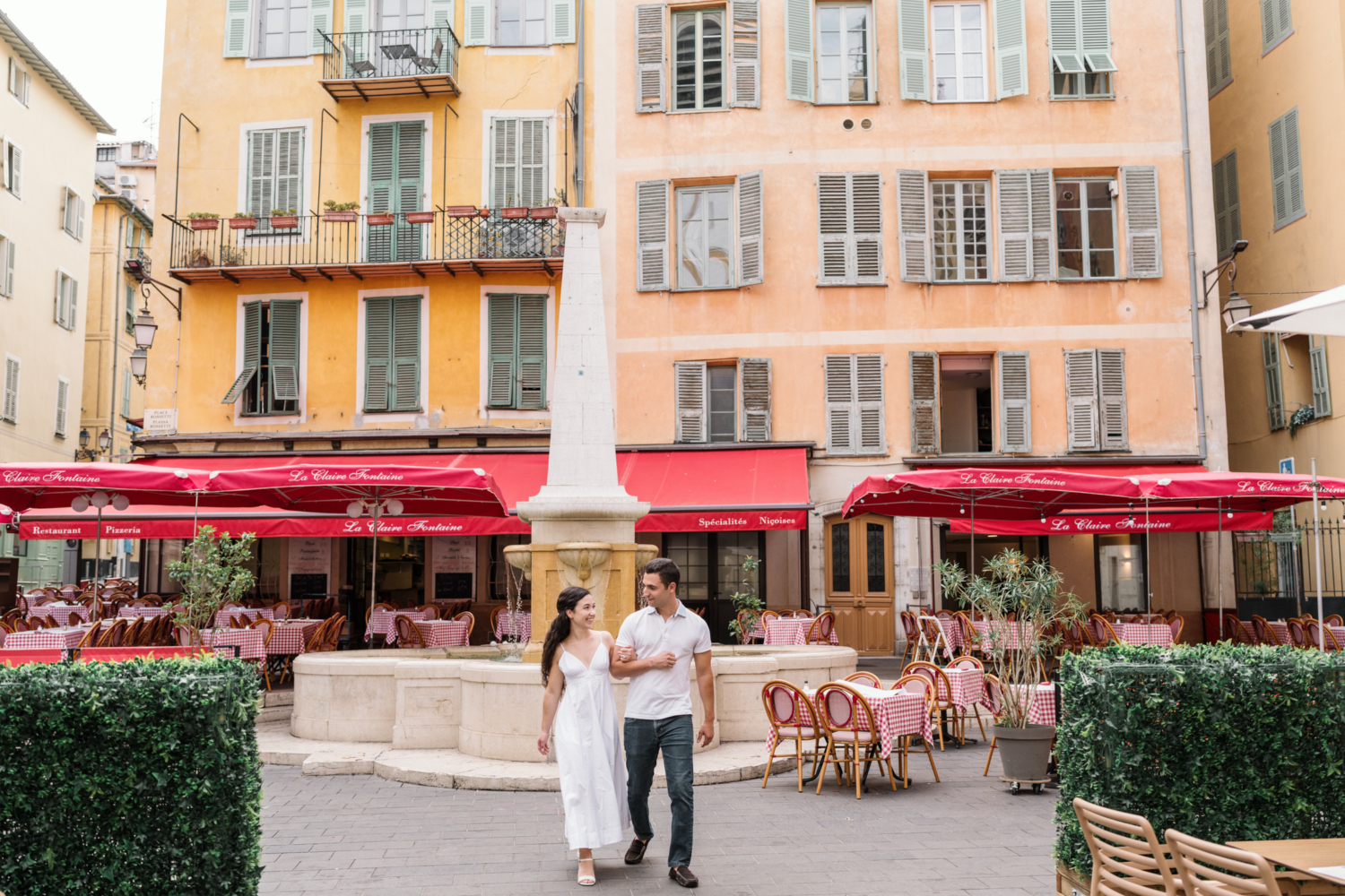 engaged couple walk arm in arm in old town nice france in front of italian restaurant