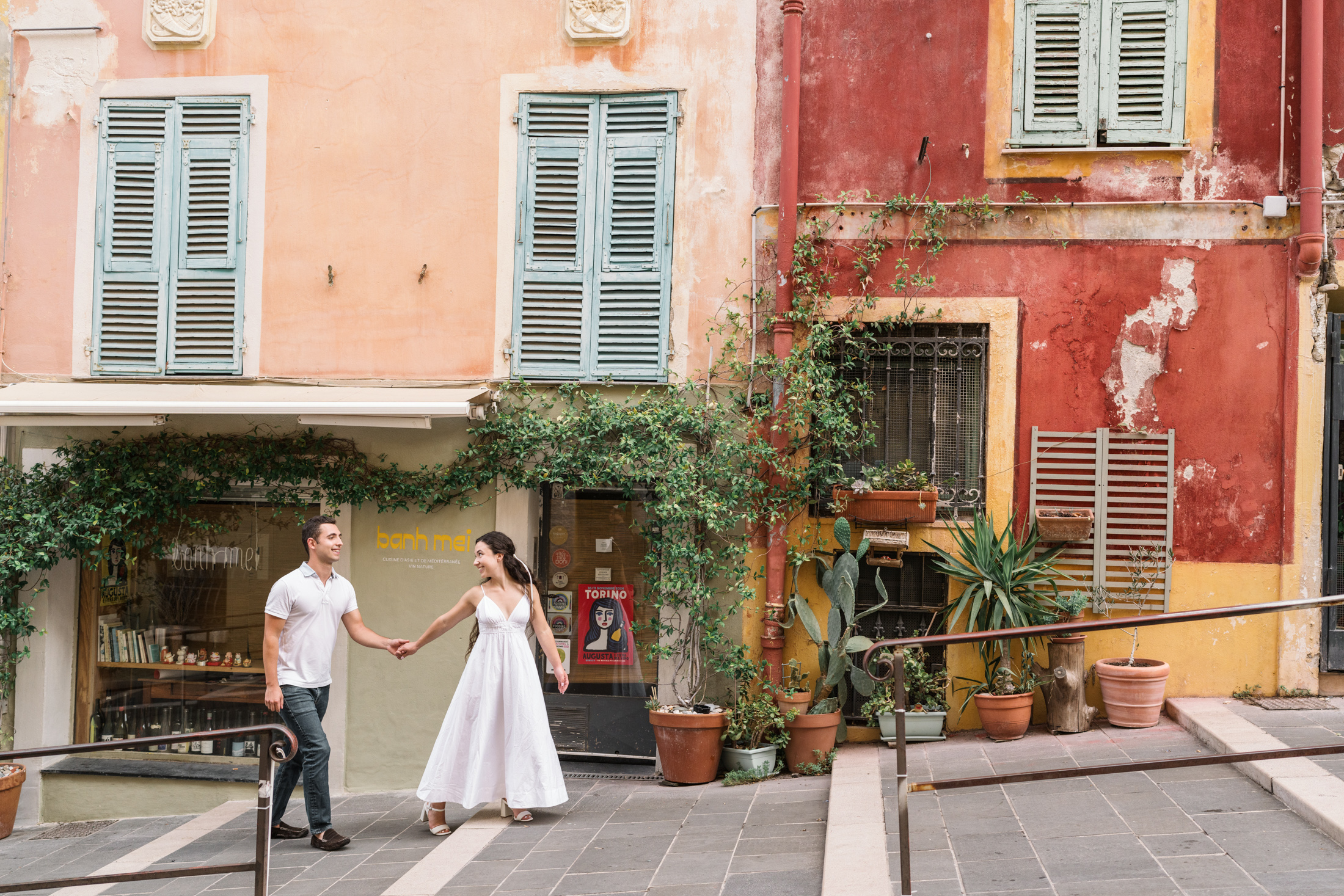 newly engaged couple walk in front of colorful building in old nice france