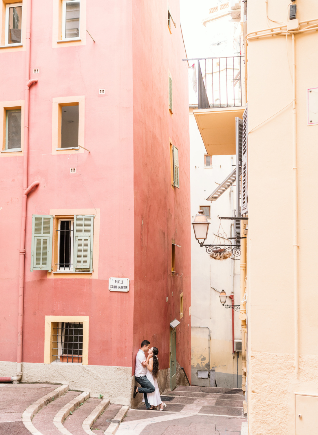 newly engaged couple embrace next to colorful building in nice france