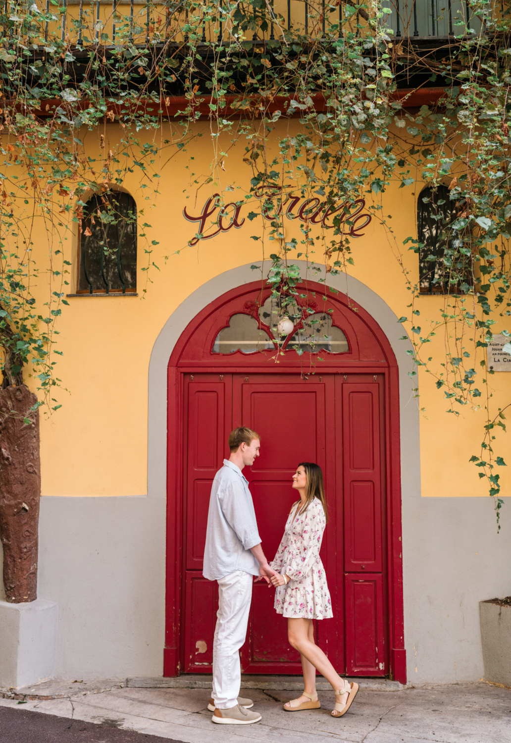 newly engaged couple hold hands in front of red door in nice france