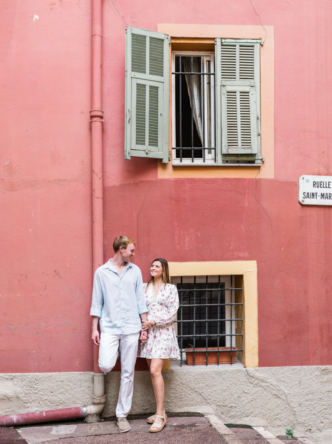 newly engaged couple pose in front of orange building in nice france