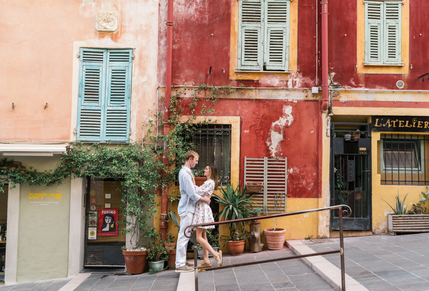 newly engaged couple embrace next to colorful buildings in nice france