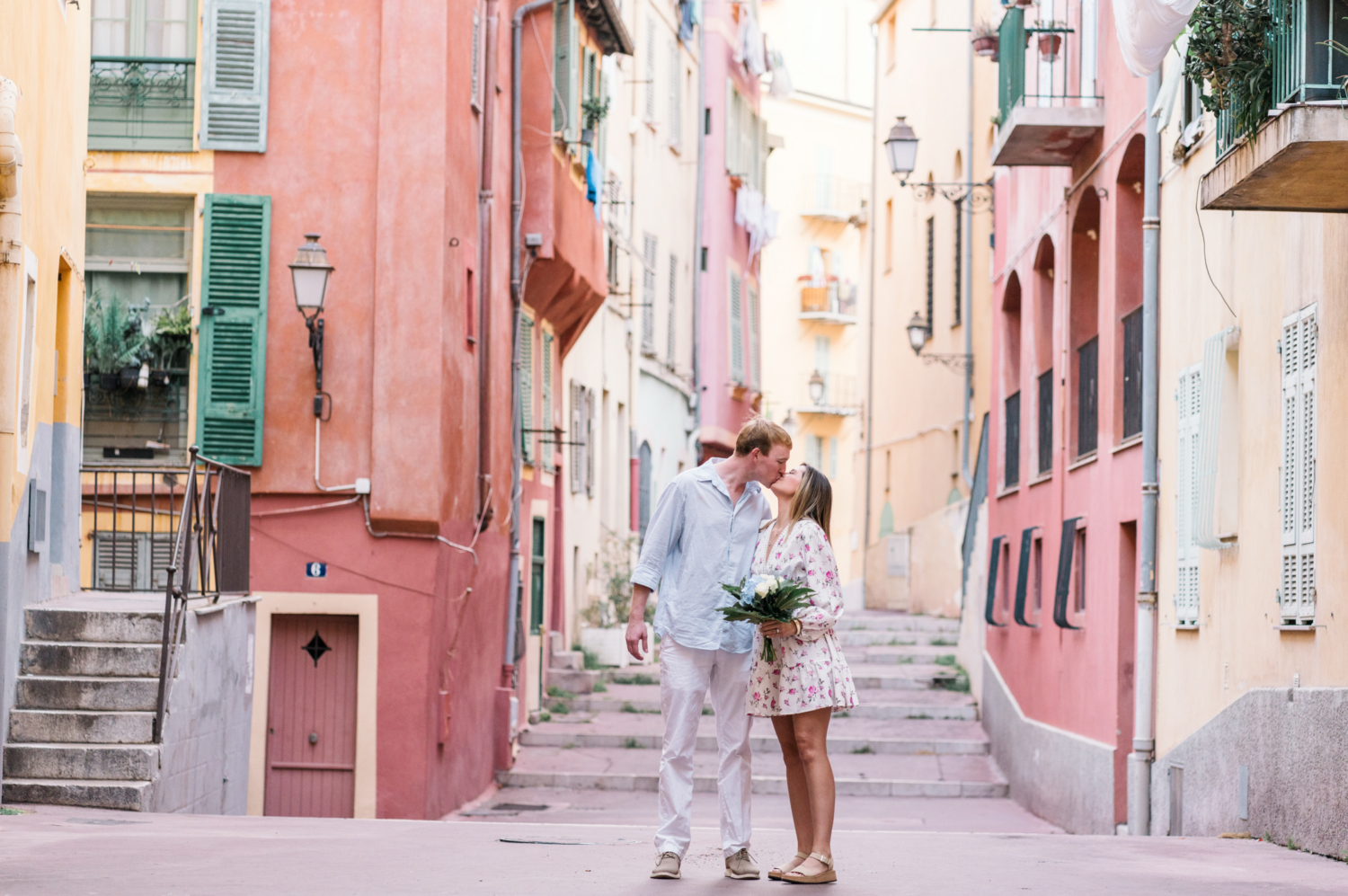 woman holding bouquet kisses man in old town nice france