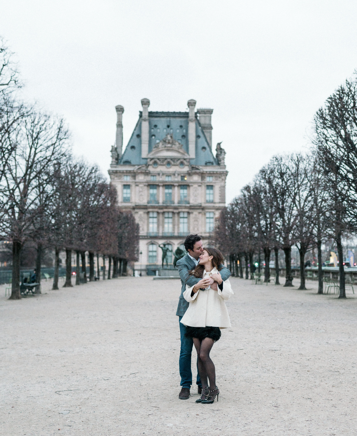 newly engaged couple man kisses woman on forehead at louvre in paris