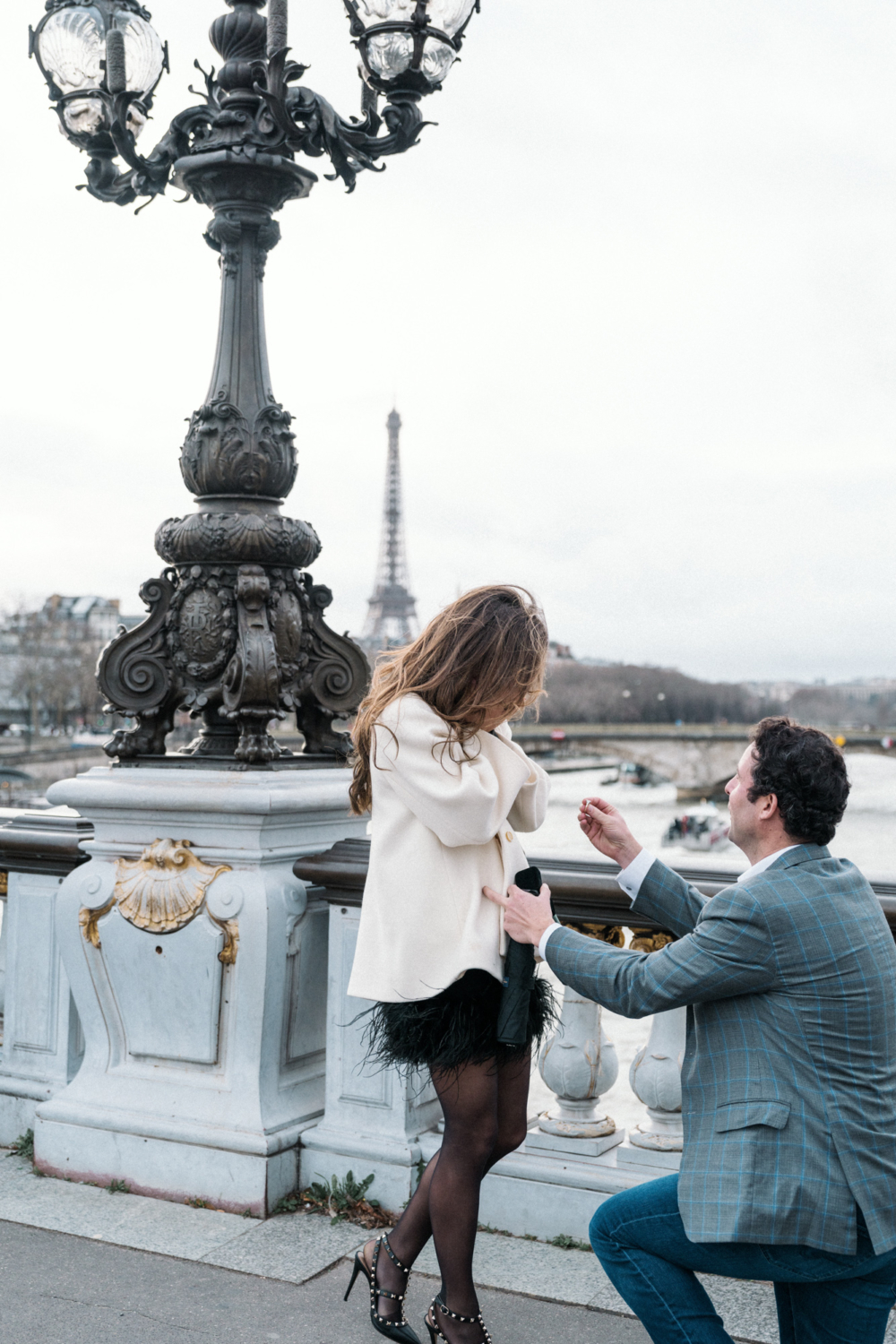 woman covers face in shock as man proposes in paris