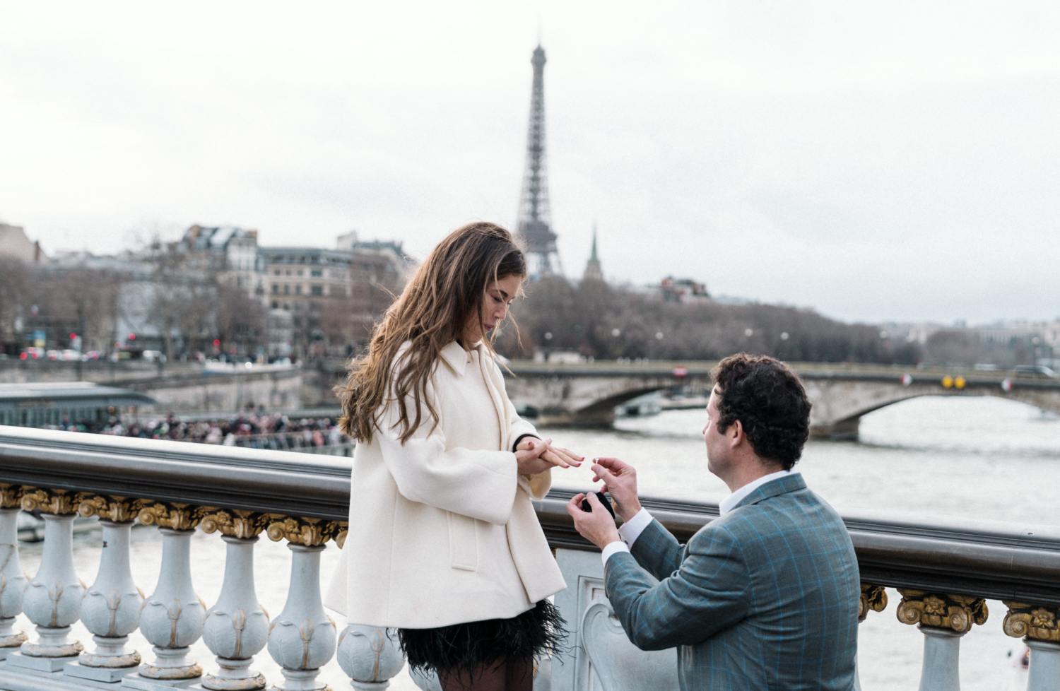 man puts engagement ring on woman's finger in paris