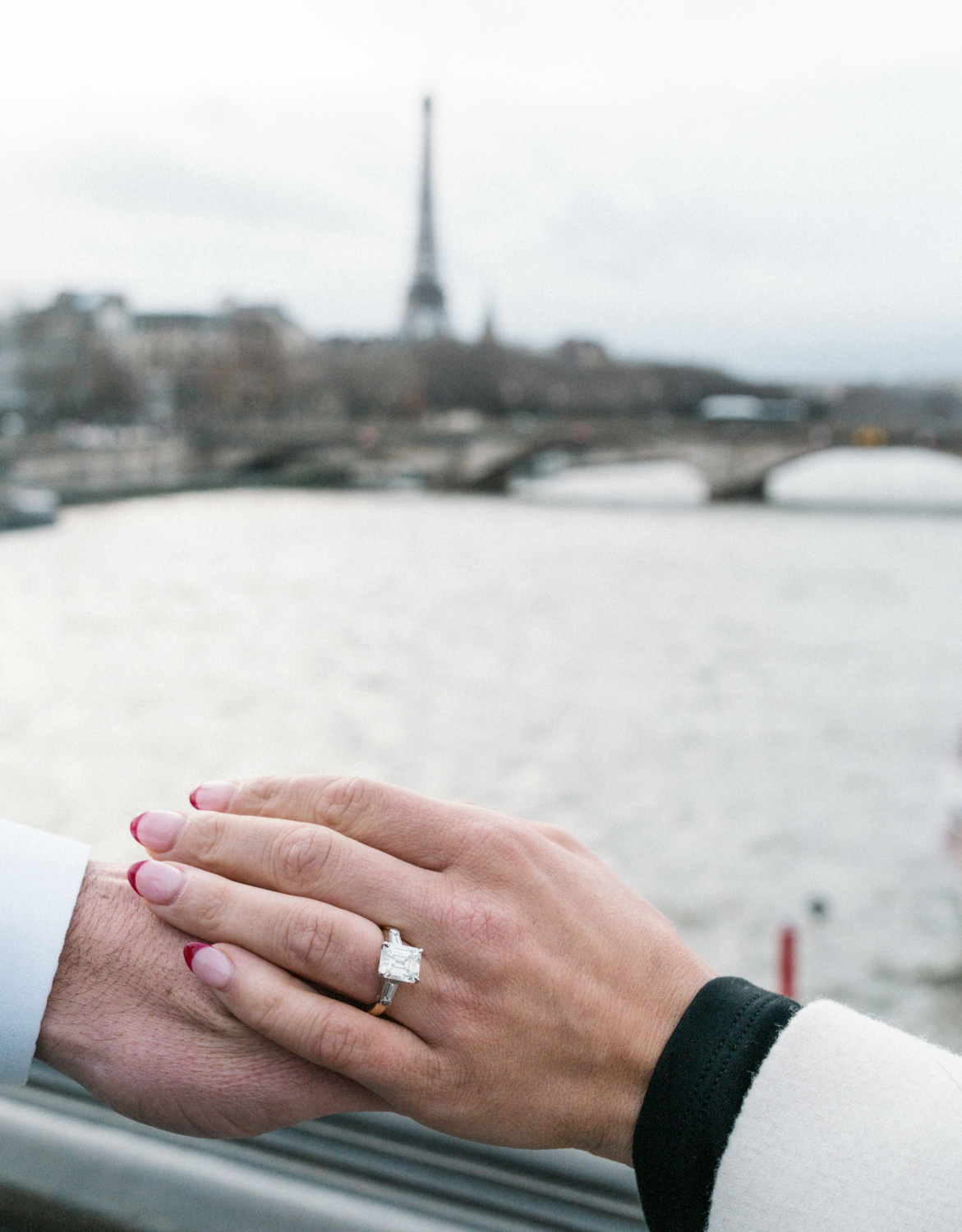 newly engaged couple photo of engagement ring with view of the eiffel tower