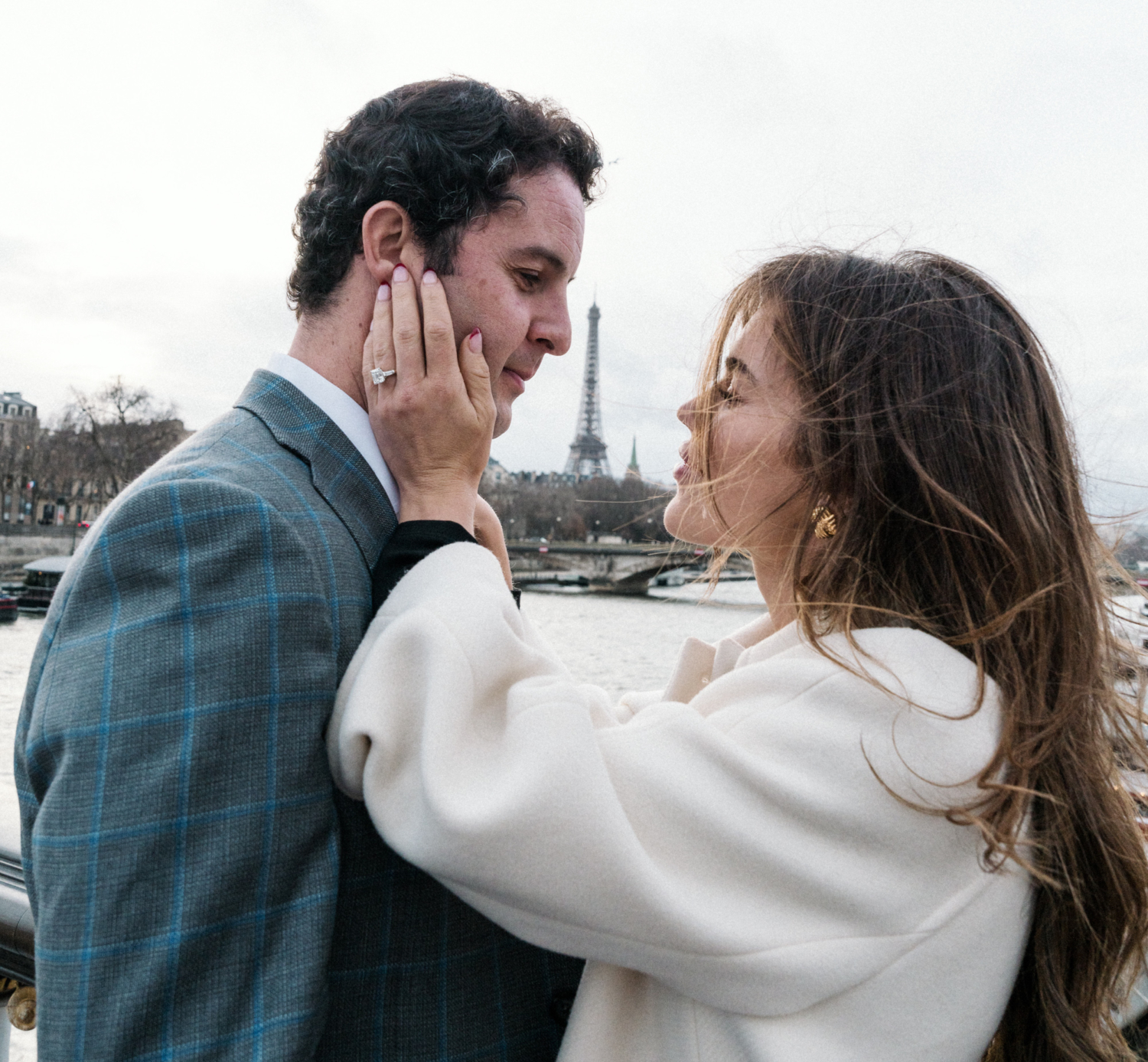 newly engaged couple woman touches mans face with view of eiffel tower