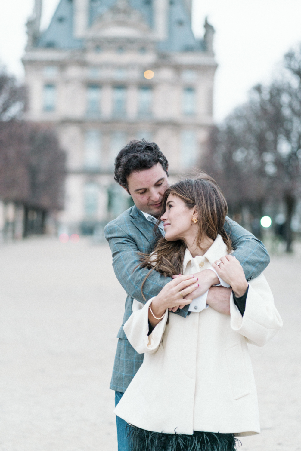 man hugs woman from behind at louvre paris