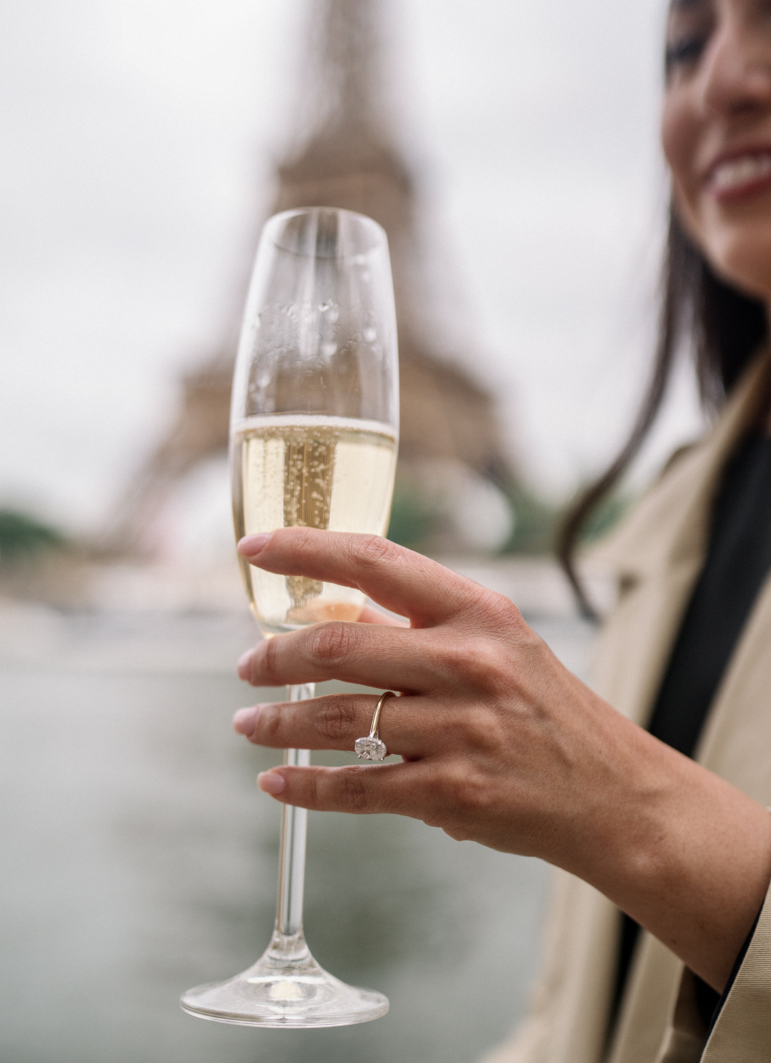 woman hold glass of champagne with new engagement ring at eiffel tower