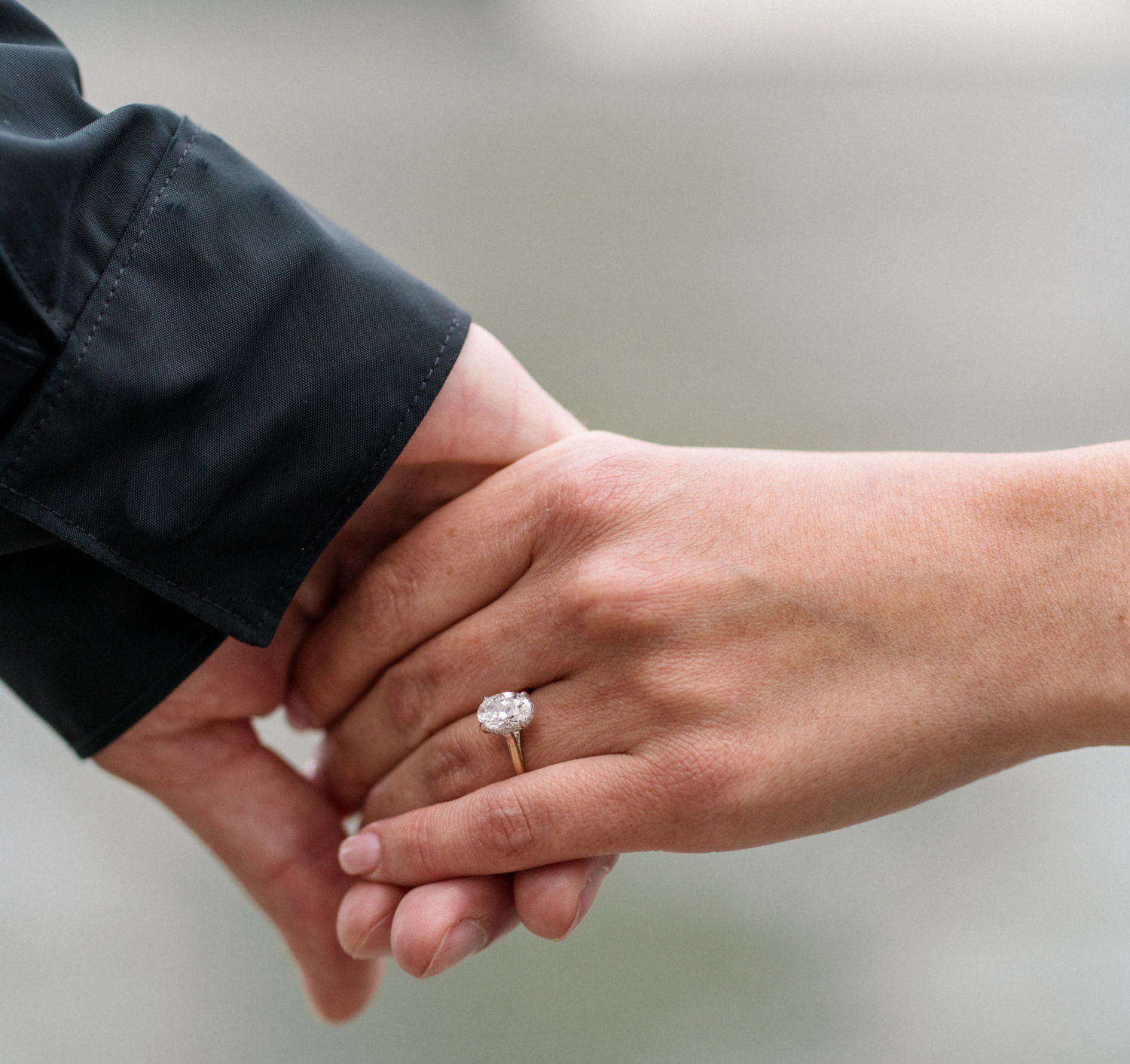 man and woman hold hands with diamond engagement ring