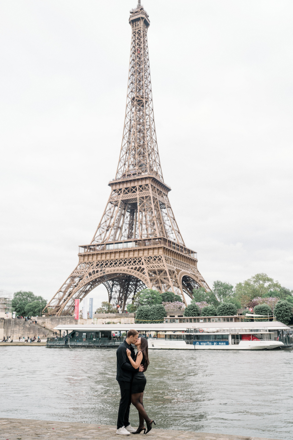 newly engaged couple kiss at eiffel tower in paris