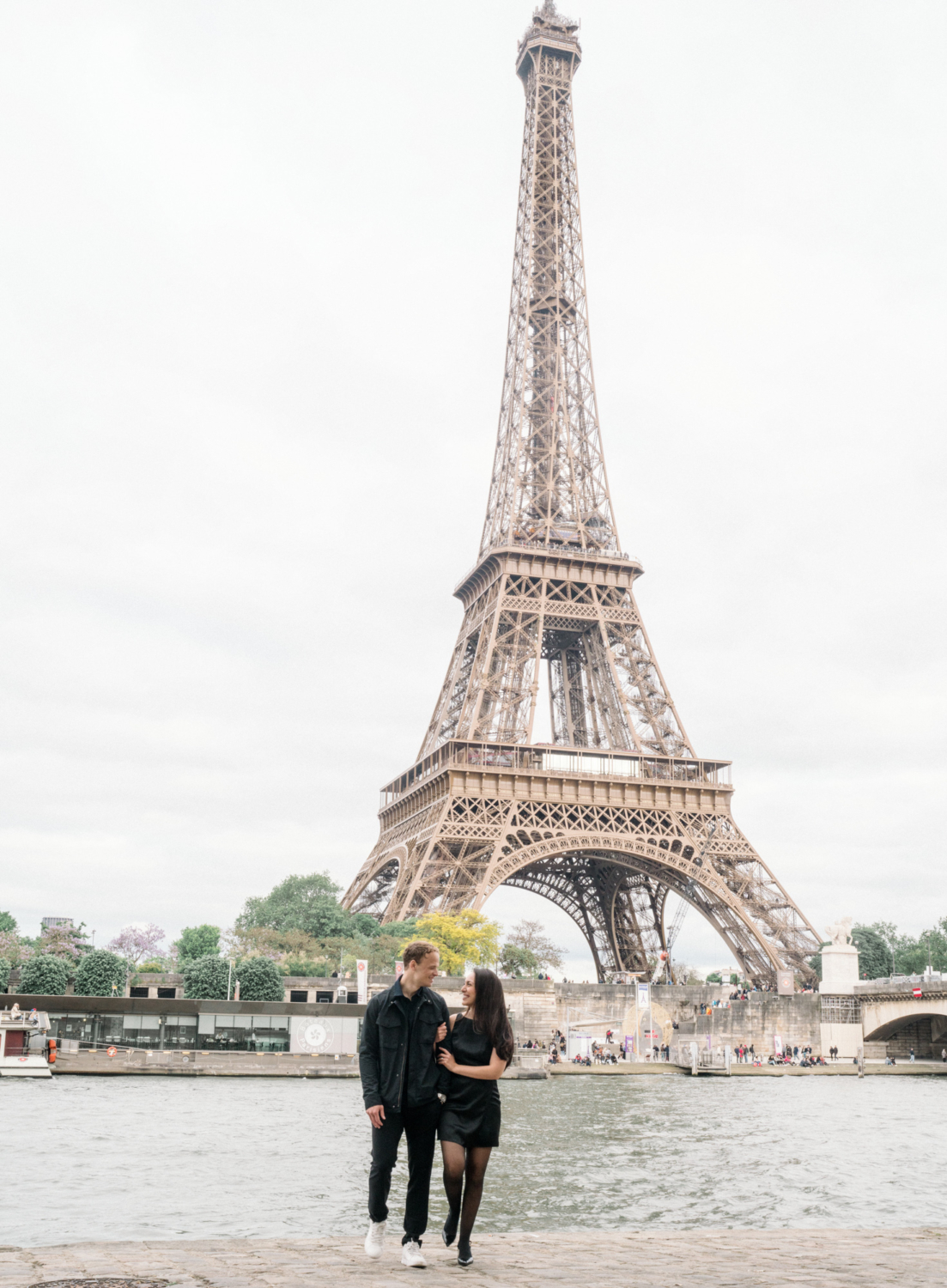 newly engaged couple walk arm in arm at eiffel tower