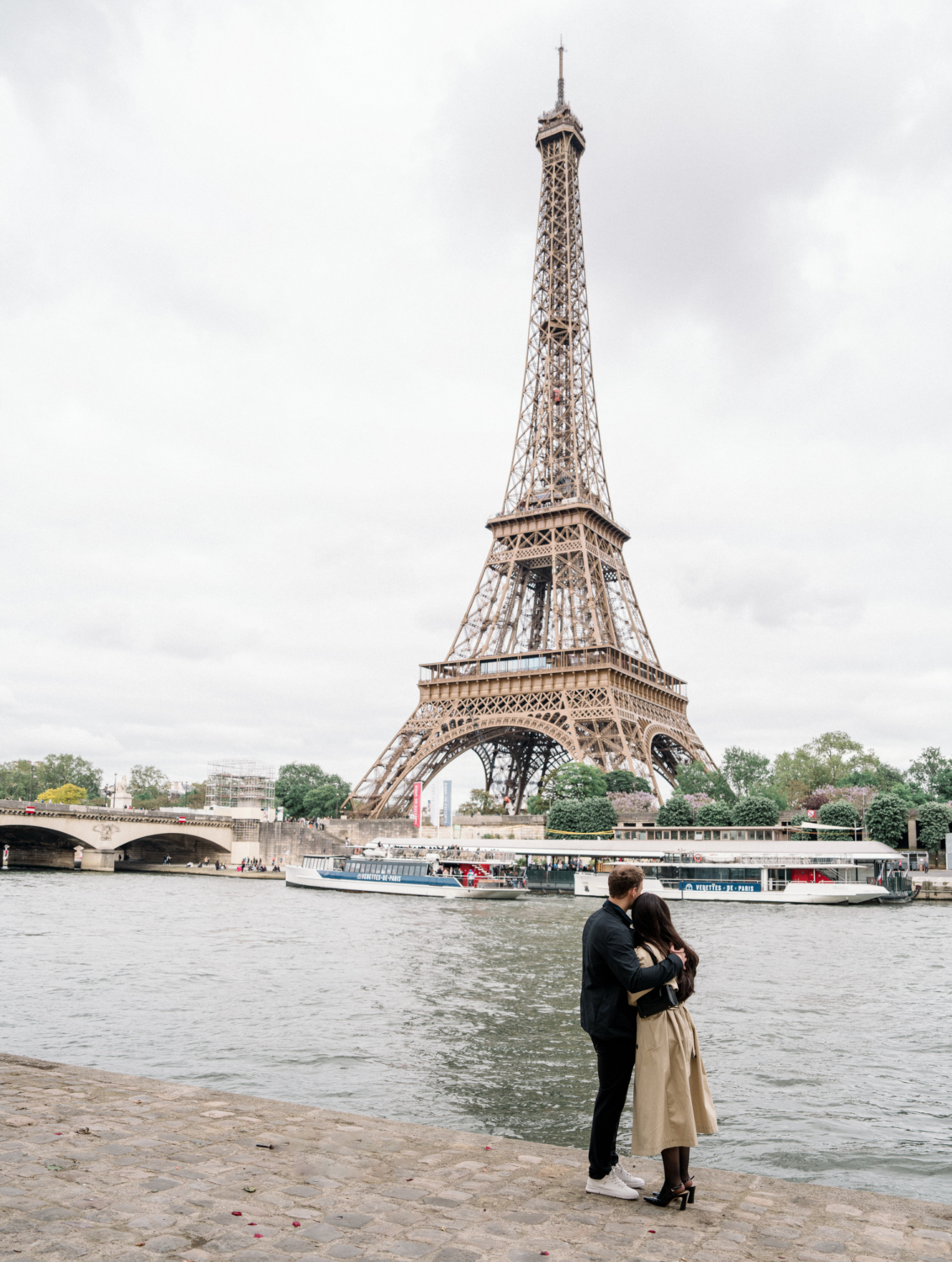 couple embrace while looking at the eiffel tower